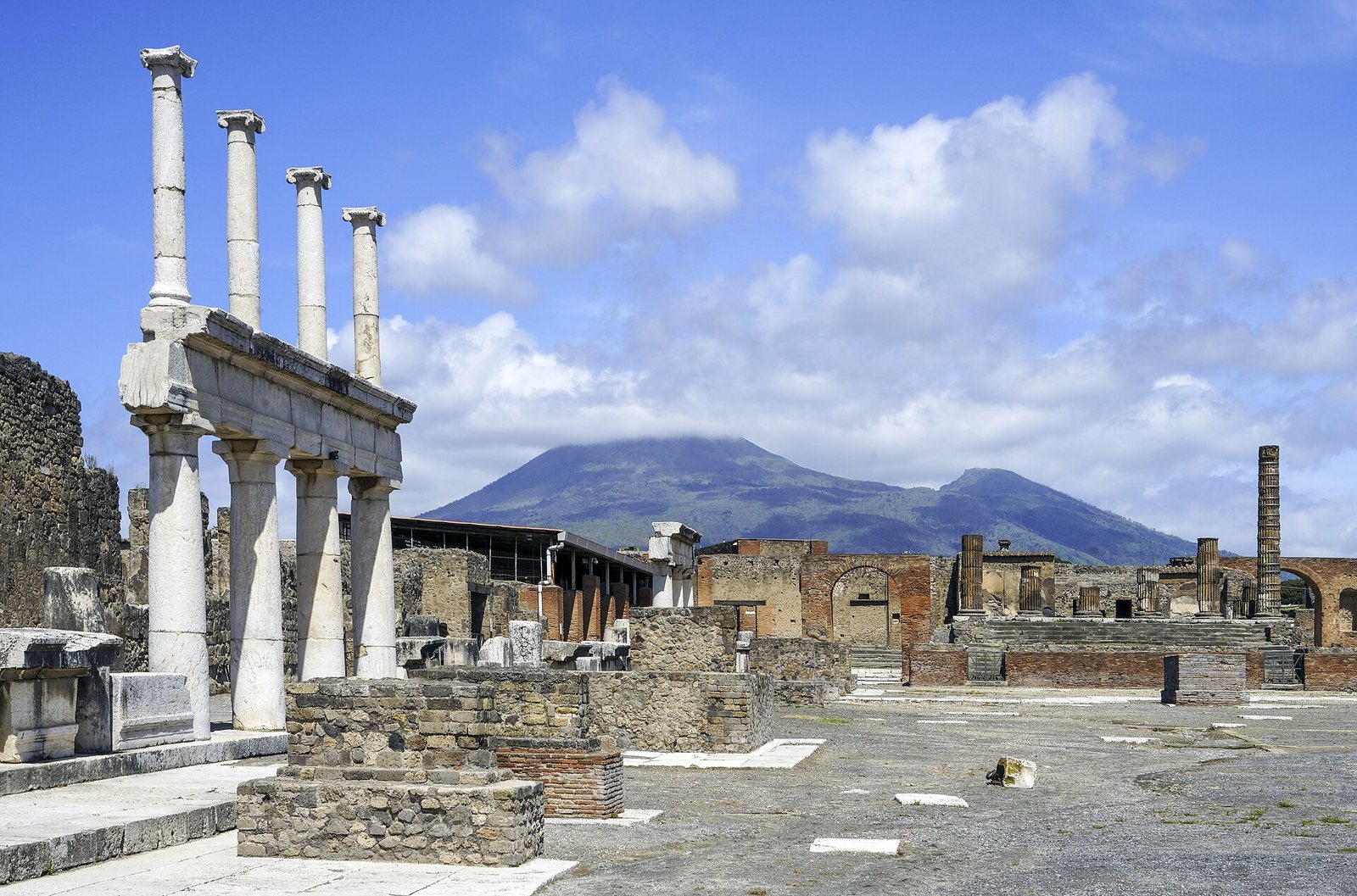 Colonne del Foro negli scavi di Pompei con il Vesuvio sullo sfondo sotto un cielo azzurro