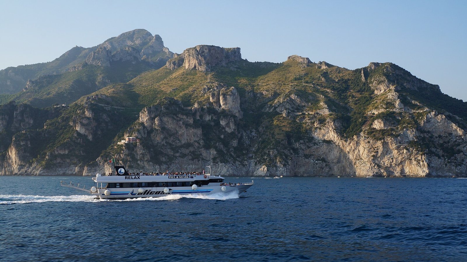 Traghetto bianco in navigazione davanti alle scogliere della Costiera Amalfitana